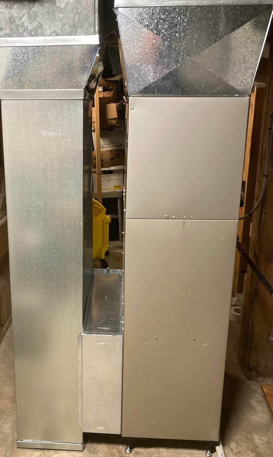 Side view of a newly installed furnace with new sheet-metal supply plenum, return duct, and filter rack